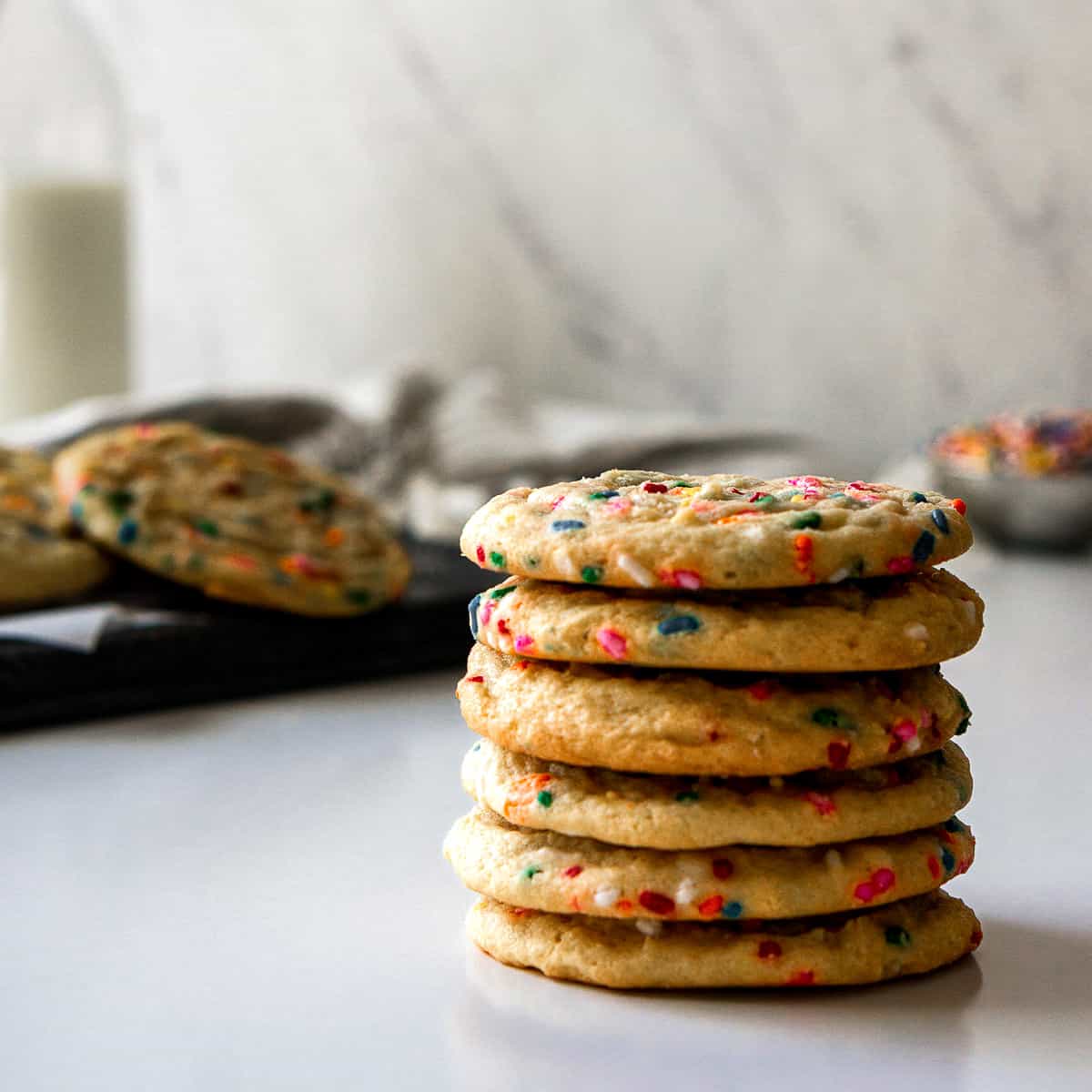Straight on view of stacked funfetti cookies on a white surface