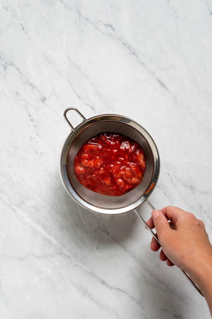 Image of cooked strawberry sauce in a mesh strainer