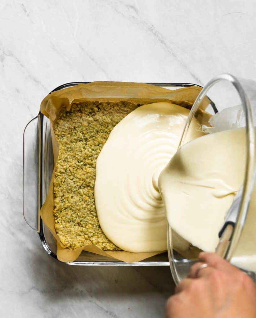 Image of cheesecake filling being poured into baked pistachio crust