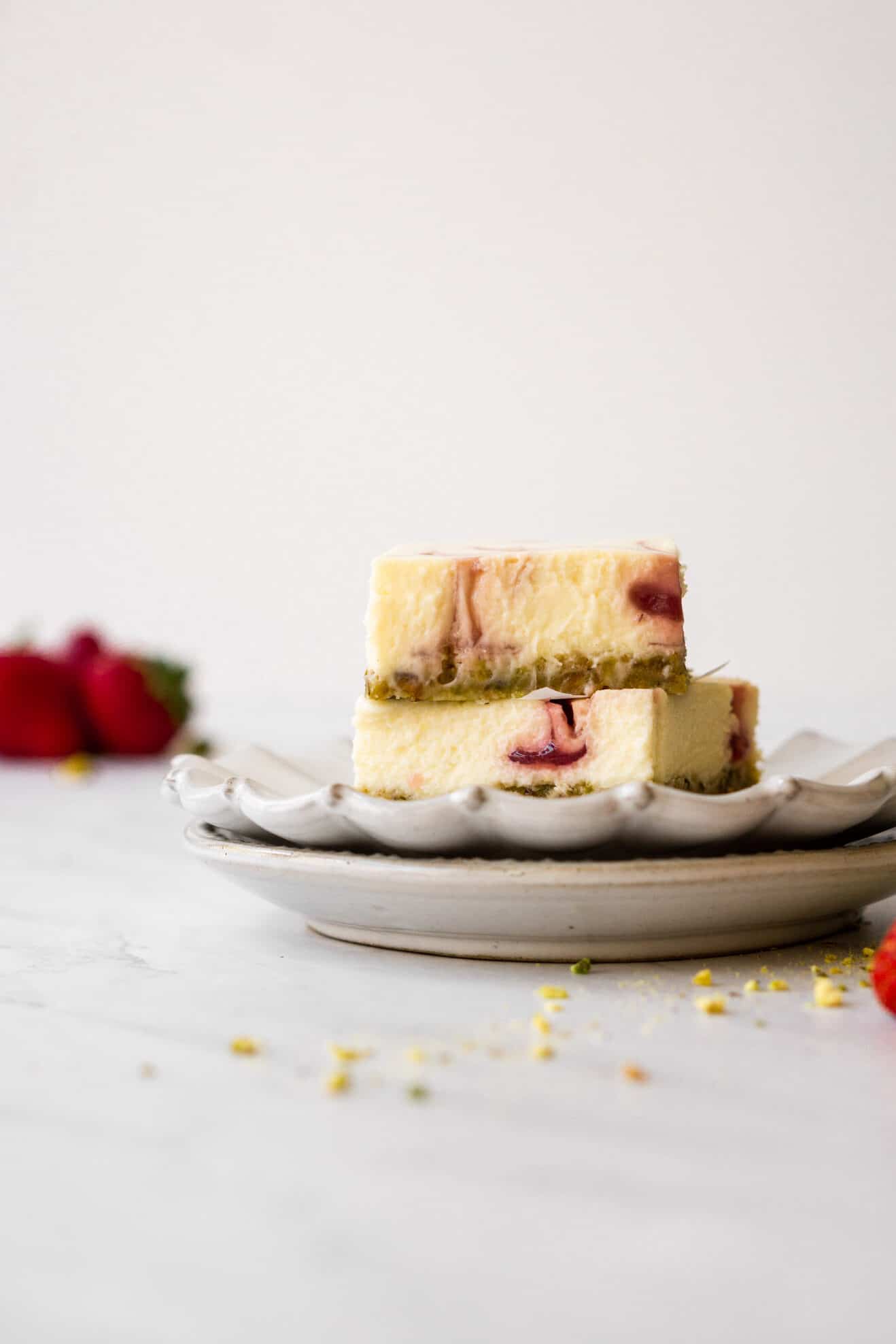 Image of strawberry pistachio cheesecake bars stacked on a serving plate