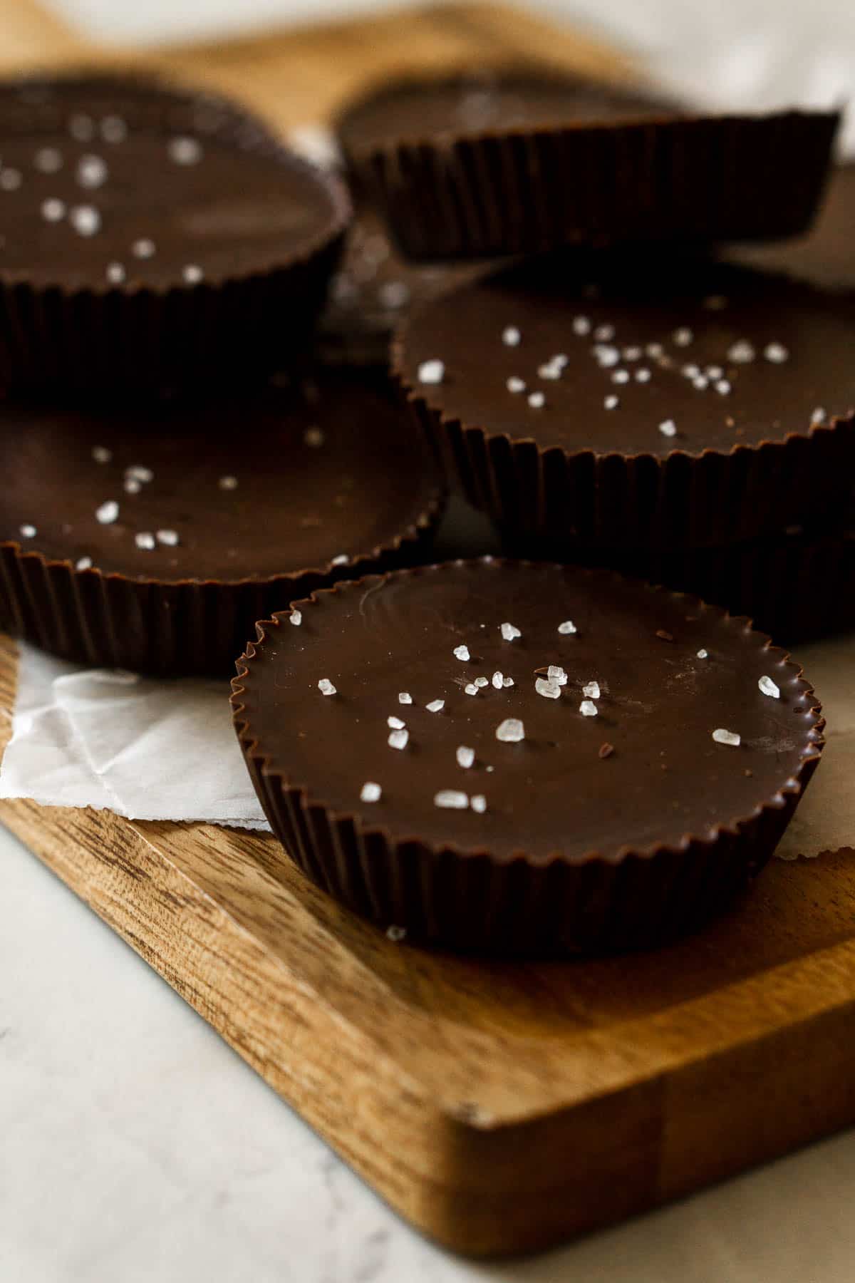 Stack of chocolate almond butter cups on a cutting board. 