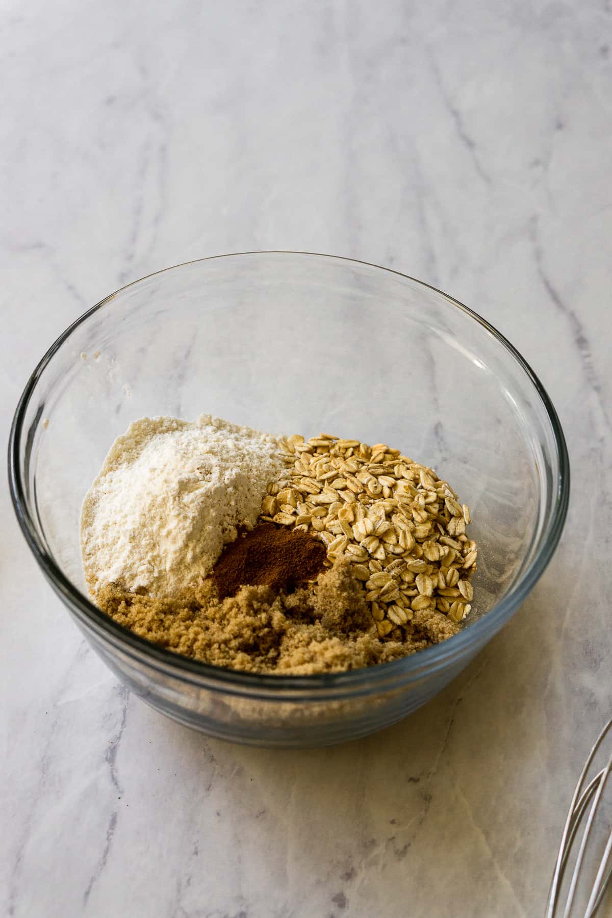 Flour, rolled oats, cinnamon, brown sugar in a glass bowl.